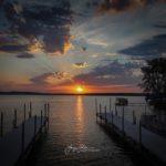 The sun sets between two wooden piers on Lake Mason. Photo by Larry Holak.